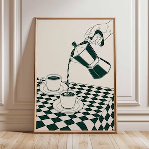 May include: A framed art print featuring a green and white illustration of coffee being poured from a moka pot into two cups on saucers. The cups sit on a checkered tablecloth. The background is a cream color.