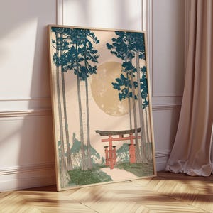 May include: Framed art print featuring a Japanese landscape with tall trees, a large moon, and a red torii gate. The artwork has a vintage aesthetic with a color palette of teal, beige, and red. The print is displayed on a wooden floor.