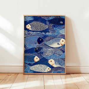Può includere: Una stampa artistica incorniciata con un motivo ripetuto di pesci stilizzati che nuotano in onde blu. I pesci hanno accenti bianchi e arancioni, e le onde sono di una tonalità di blu più scura. L'opera d'arte è esposta su un pavimento di legno.