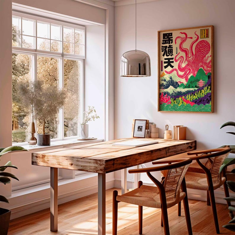 May include: A framed Japanese-style art print featuring a pink octopus with Japanese text. The artwork is set against a backdrop of mountains, a pagoda, and colorful foliage. The print hangs above a wooden desk with two woven chairs.