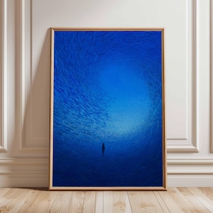 Può includere: Stampa artistica incorniciata raffigurante una persona in un vortice blu intenso e vorticoso. L'opera d'arte ha uno stile minimalista, con un focus sul contrasto tra la figura e le forme astratte circostanti. La cornice è di colore marrone chiaro.