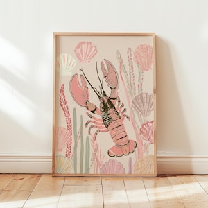 May include: A framed wall art print featuring a central pink lobster illustration surrounded by various seashells and seaweed in shades of soft pink, cream, and muted green against a light beige background, enclosed in a light wood frame.