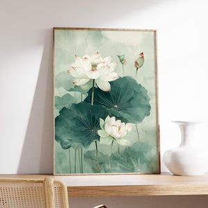 Puede incluir: Una impresi&oacute;n art&iacute;stica enmarcada que presenta una pintura de acuarela de flores de loto blancas con hojas verdes. La obra de arte tiene una paleta de colores suaves y apagados con tonos de verde y blanco, creando una est&eacute;tica serena y natural.
