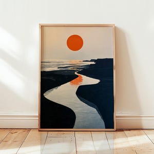 Pode incluir: Uma impressão de arte de parede retangular emoldurada com uma ilustração de paisagem minimalista. Um sol laranja sólido paira sobre uma costa azul-escura, com um rio sinuoso refletindo a luz laranja enquanto flui pelo centro do terreno escuro.
