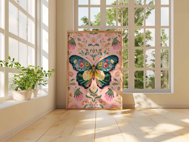 May include: A framed art print featuring a colorful butterfly design. The butterfly has blue, green, yellow, and floral details. The background is a soft pink with floral and botanical elements. The artwork is displayed in a room with natural light.
