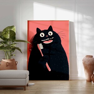 Op de afbeelding: Een ingelijste kunstdruk met een cartoon zwarte kat die zijn tanden poetst met een roze tandenborstel. De kat heeft grote witte ogen en een brede, tandige grijns. De achtergrond is effen koraalkleurig.