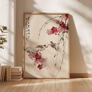 Peut inclure: Une impression encadr&eacute;e d'une peinture de style asiatique traditionnel. Deux petits oiseaux sont perch&eacute;s sur des branches orn&eacute;es de fleurs rouges et roses. L'&oelig;uvre comprend de la calligraphie sur le c&ocirc;t&eacute; gauche, le tout sur un fond cr&egrave;me.