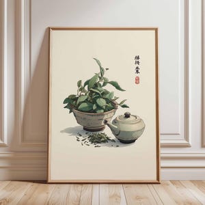 Puede incluir: Impresión enmarcada que presenta una naturaleza muerta con elementos de té. Se muestra un cuenco con hojas de té verde, una tetera pequeña y hojas de té esparcidas. La obra de arte tiene una paleta de colores suaves y una estética asiática tradicional.