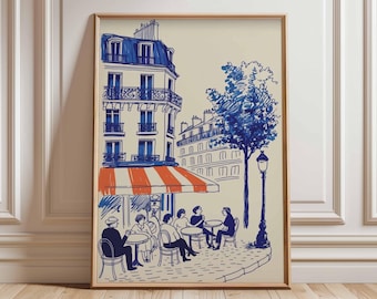 Puede incluir: Una impresión artística enmarcada que representa una escena de café parisino. La ilustración presenta un edificio con techo y ventanas azules, un toldo a rayas naranja y blanco, y personas sentadas en mesas. También se incluye un árbol y una farola.