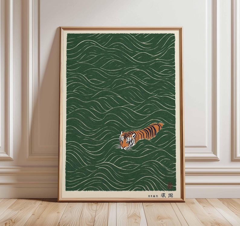 May include: Framed art print featuring a tiger swimming in green water with white wave patterns. The tiger has orange and black stripes. The artwork is in a wooden frame and is displayed on a wooden floor.