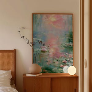 May include: A framed painting depicts a serene water scene with pink and blue hues, featuring swans and lily pads. The artwork hangs above a wooden cabinet with a vase and a lamp. The room has a neutral color palette.