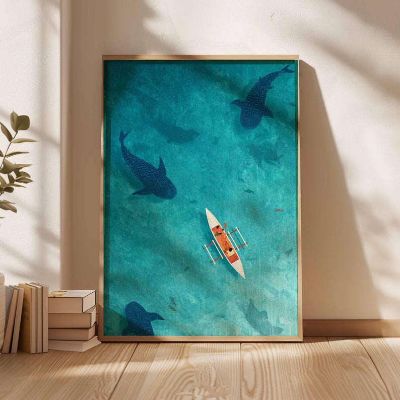 May include: A framed art print depicts a turquoise ocean scene with whale sharks and a small boat. The boat has two people inside. The whale sharks are dark blue, and the boat is white and orange. The art print is in a wooden frame.