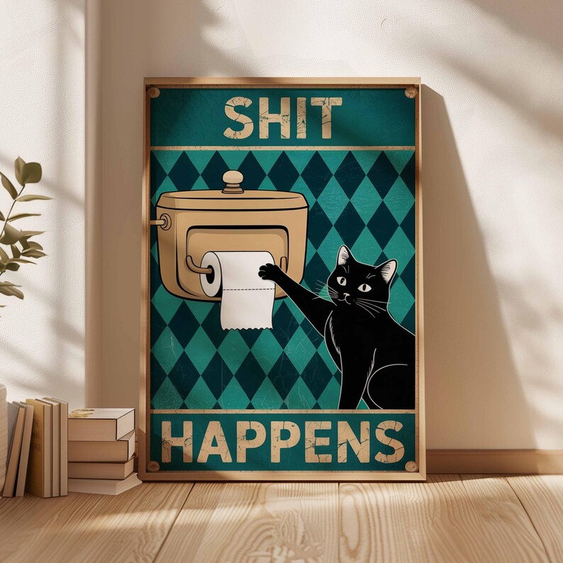 May include: A framed poster with the words "SHIT HAPPENS" above and below an illustration of a black cat reaching for toilet paper. The background has a teal diamond pattern.