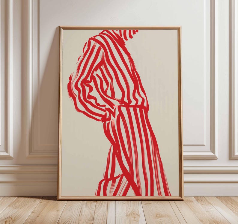 Puede incluir: Impresi&oacute;n art&iacute;stica enmarcada que representa una figura con ropa a rayas rojas y blancas. La obra de arte es una ilustraci&oacute;n minimalista con pinceladas audaces, sobre un fondo neutro. El marco es de color madera clara.