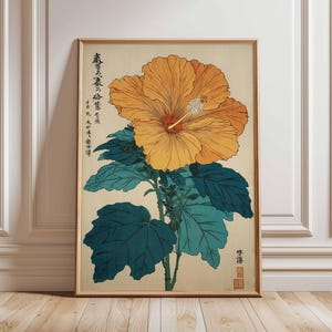 May include: A framed botanical print of a large orange hibiscus flower with a red center and white stamen. The flower is set against a beige background with teal leaves and stems. Japanese text is visible on the top left of the print.
