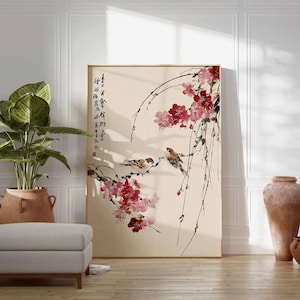Peut inclure: Une &oelig;uvre d'art encadr&eacute;e repr&eacute;sentant une peinture de style asiatique avec des oiseaux et des fleurs roses. De la calligraphie est visible sur le c&ocirc;t&eacute; gauche. L'&oelig;uvre est expos&eacute;e dans une pi&egrave;ce avec une plante, un tabouret et des pots en terre cuite.