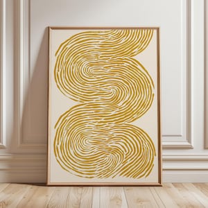 Könnte beinhalten: Abstrakter Kunstdruck mit cremefarbenem Hintergrund und zwei wirbelnden, senfgelben, fingerabdruckartigen Formen. Das Kunstwerk ist in Naturholz gerahmt und bietet einen modernen, minimalistischen Look. Der Druck wird vor einer weißen Wand und einem Holzboden präsentiert.