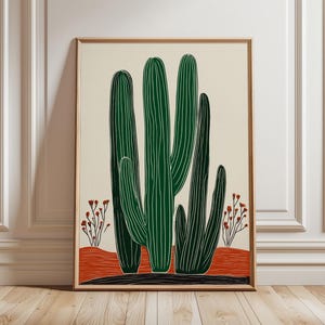 May include: A framed art print featuring a stylized illustration of a cactus. The cactus is depicted in shades of green with white lines, set against a cream background. The artwork includes red and black accents, and is framed in a light wood.