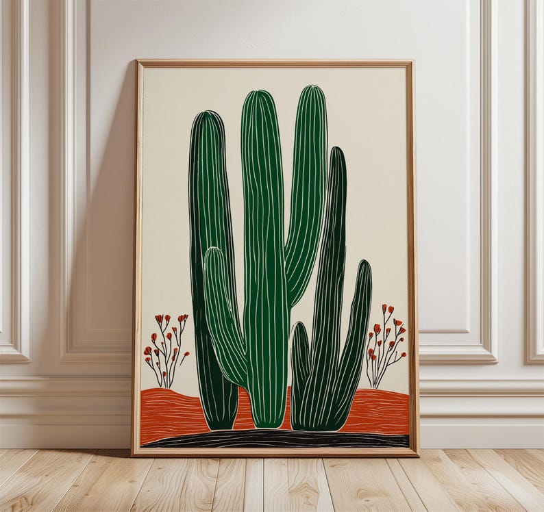 May include: A framed art print featuring a stylized illustration of a cactus. The cactus is depicted in shades of green with white lines, set against a cream background. The artwork includes red and black accents, and is framed in a light wood.