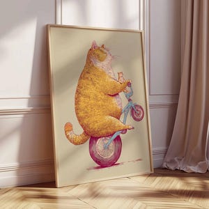 K&ouml;nnte beinhalten: Gerahmter Kunstdruck mit einer Illustration einer gro&szlig;en, orangefarbenen Katze, die auf einem blauen Fahrrad mit einem kleinen K&auml;tzchen f&auml;hrt. Die Katze sitzt auf einem gro&szlig;en, pinkfarbenen Rad. Das Kunstwerk hat einen hellbeigen Hintergrund.