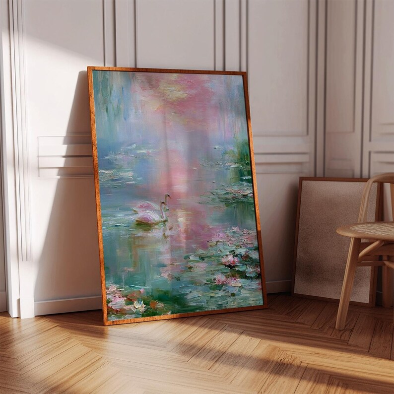 May include: A framed painting depicts a serene pond scene with swans and lily pads. The artwork features soft brushstrokes in shades of pink, blue, and green, creating a tranquil and impressionistic aesthetic. The wooden frame adds a touch of warmth.
