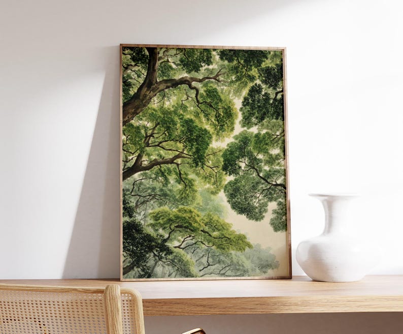 May include: A framed art print featuring a watercolor painting of a forest canopy. The artwork showcases lush green foliage and tree branches, with a soft, diffused light filtering through the leaves. The print is displayed on a wooden shelf.