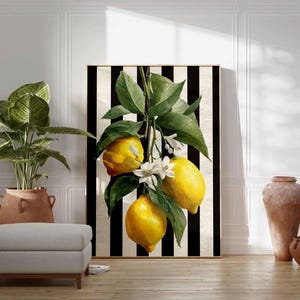May include: A framed art print featuring a vibrant lemon branch with bright yellow fruit and green leaves against a black and white striped background. The artwork includes white blossoms and is displayed in a room with a potted plant and a neutral-toned ottoman.