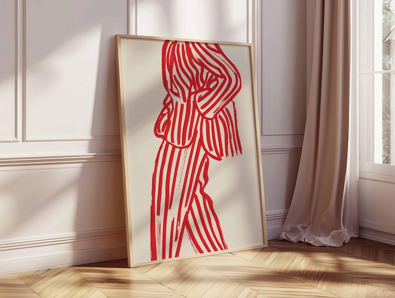 K&ouml;nnte beinhalten: Ein gerahmter Kunstdruck mit einer rot-wei&szlig; gestreiften Figur. Das Kunstwerk zeigt eine Person in einem Anzug mit kr&auml;ftigen vertikalen Streifen. Der Druck wird vor einem neutralen Hintergrund gezeigt, der an einer wei&szlig;en Wand und einem Holzboden lehnt.
