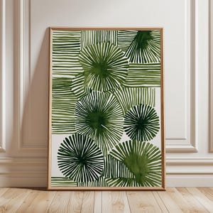 Op de afbeelding: Abstracte kunstprint met een patroon van groene radiale en lineaire vormen op een witte achtergrond. Het kunstwerk is ingelijst in een natuurlijke houttint, wat een moderne esthetiek creëert. Het ontwerp bevat verschillende groentinten, ideaal voor interieurdecoratie.