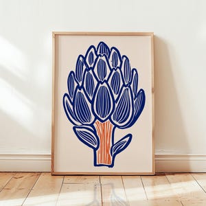 Puede incluir: Una lámina de arte enmarcada que presenta una ilustración estilizada de una alcachofa. La alcachofa está representada con líneas azules audaces sobre un fondo crema claro, con un tallo naranja texturizado en la base, en un marco de madera clara.