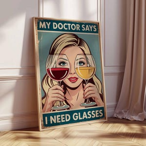 May include: A framed vintage-style poster with the text "MY DOCTOR SAYS I NEED GLASSES." The artwork features a blonde woman holding a glass of red wine in front of one eye and a glass of white wine in front of the other.