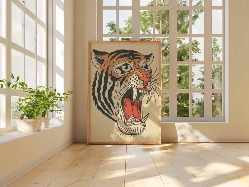 May include: A framed illustration of a tiger's head with an open mouth, showcasing sharp teeth and a red interior. The tiger has orange and black stripes, set against a cream background. The artwork is displayed in a room with a window and plants.