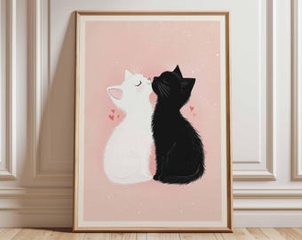 May include: A framed art print depicting two cartoon cats, one white and one black, in an embrace. The background is a soft pink with small pink hearts. The print is presented in a wooden frame.