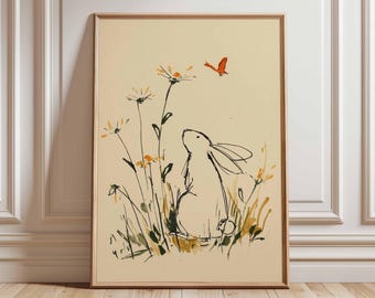 May include: A framed art print featuring a whimsical illustration of a white rabbit gazing at an orange butterfly. The artwork includes yellow and black wildflowers and green grass against a cream background. The print is in a wooden frame.