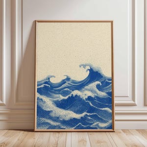 May include: A framed art print depicting ocean waves in a pointillist style. The image uses blue and white dots against a beige backdrop. The waves are rendered with detail, creating a sense of motion. The artwork is framed in a wooden border.