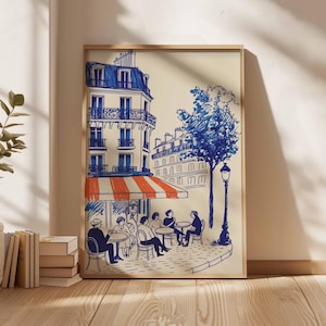 K&ouml;nnte beinhalten: Gerahmter Kunstdruck, der eine Pariser Caf&eacute;szene darstellt. Die Illustration zeigt ein Geb&auml;ude mit blauem Dach, eine rot-wei&szlig; gestreifte Markise und Personen, die an Tischen sitzen. Ein blauer Baum und eine Stra&szlig;enlaterne sind ebenfalls zu sehen.