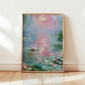 May include: A framed painting of a serene water scene with two white swans. The artwork features a soft color palette of pink, blue, and green, with lily pads and reflections in the water. The painting is displayed on a wooden floor.