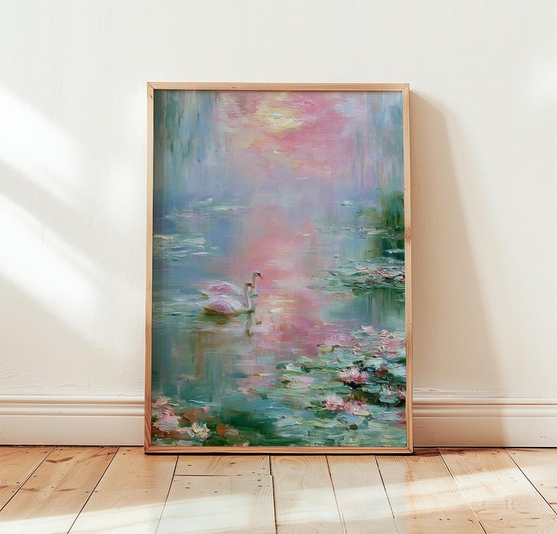 May include: A framed painting of a serene water scene with two white swans. The artwork features a soft color palette of pink, blue, and green, with lily pads and reflections in the water. The painting is displayed on a wooden floor.