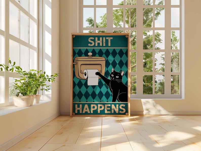 May include: A framed poster with the words "SHIT HAPPENS" and a cartoon image of a black cat reaching for toilet paper. The background is teal with a diamond pattern. The poster is in a room with a window and plants.