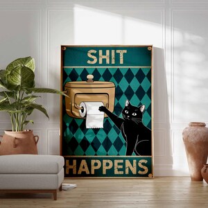 May include: A framed poster with the words "SHIT HAPPENS" and a black cat reaching for toilet paper. The background features a teal diamond pattern. A tan toilet paper dispenser is also visible.