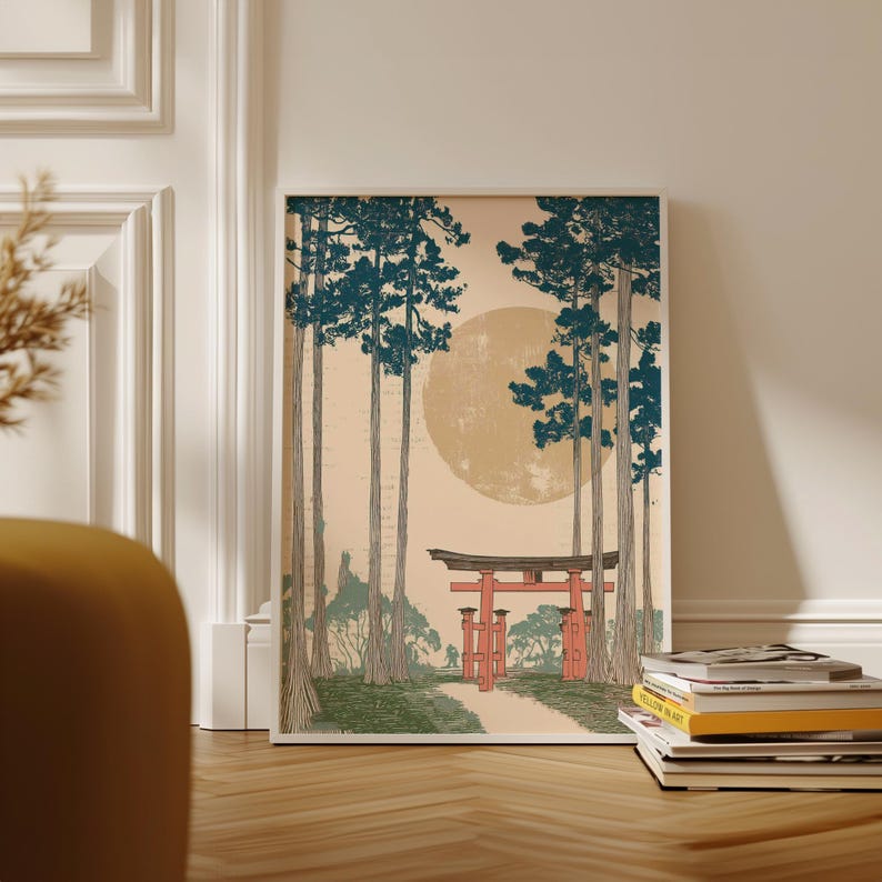 May include: Framed art print featuring a Japanese landscape. The artwork depicts a red torii gate at the end of a path, tall trees with teal foliage, and a large yellow sun. The print is displayed on a wooden floor.