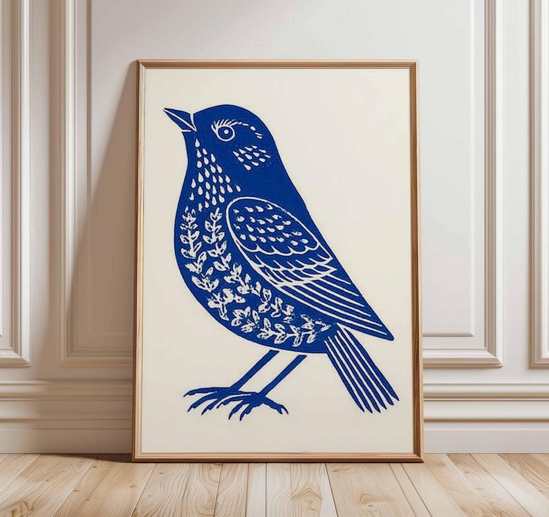 May include: A framed print featuring a stylized blue bird illustration. The bird is depicted with intricate details, including leaf-like patterns on its chest and wings. The artwork is set against a cream-colored background and framed in a wooden frame.