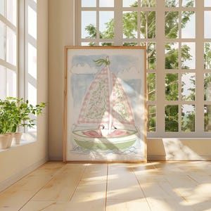 May include: Watercolor painting of a sailboat with a pink and white checkered sail, floral details, and two pink flamingos. The artwork is in a wooden frame, set against a window with natural light and greenery.