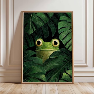 Peut inclure: Impression d'art encadrée représentant une grenouille de dessin animé cachée parmi des feuilles vertes luxuriantes. La grenouille a de grands yeux avec des centres jaunes et un corps vert clair. L'œuvre d'art est sur fond sombre, créant un contraste saisissant.