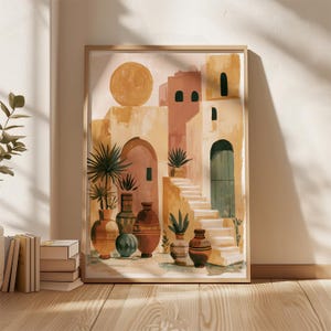 Peut inclure: Une affiche encadr&eacute;e repr&eacute;sentant un soleil et des b&acirc;timents aux tons p&ecirc;che, beige et jaune. L'&oelig;uvre pr&eacute;sente des arcades, des escaliers et des vases d&eacute;coratifs avec des plantes. L'affiche est expos&eacute;e sur un sol en bois.