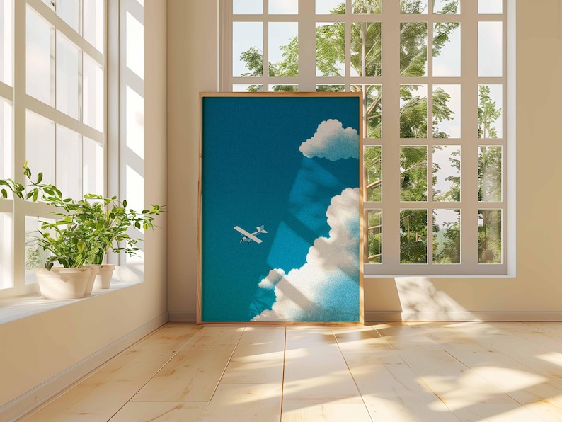 Peut inclure: Une affiche encadr&eacute;e repr&eacute;sentant un ciel bleu avec des nuages blancs et un petit avion blanc. L'&oelig;uvre est expos&eacute;e dans une pi&egrave;ce avec la lumi&egrave;re naturelle d'une grande fen&ecirc;tre et une plante en pot sur le rebord.
