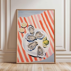 Puede incluir: Impresión artística enmarcada que presenta un bodegón de ostras en un plato blanco, con rodajas de limón. El plato descansa sobre un paño a rayas rojas y blancas. La obra de arte tiene un fondo azul claro y un marco de madera.