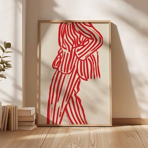 K&ouml;nnte beinhalten: Abstrakter Kunstdruck mit einer Figur in einem rot-wei&szlig; gestreiften Anzug. Das Kunstwerk ist in einem hellen Holzrahmen gerahmt und lehnt an einer Wand. Der Druck hat einen minimalistischen Stil und eine kr&auml;ftige Farbpalette.