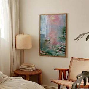 May include: A framed artwork depicting a serene water scene with pink and green hues. The painting features water lilies and a soft, impressionistic style. The artwork is displayed on a beige wall, adding a touch of elegance to the room.