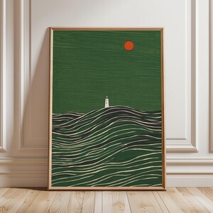 Op de afbeelding: Een ingelijste kunstprint met een minimalistisch landschap. Het kunstwerk toont een witte vuurtoren op een groene heuvel, met gestileerde golven op de voorgrond. Een rode zon staat in de rechterbovenhoek, tegen een groene lucht. De lijst is van natuurlijk hout.
